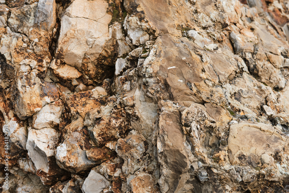 Rock of attractive shade and bulge. Unusual beautiful orange stone texture. Minimalistic geological background for desktop or advertising. Light yellow stone on rock close up.