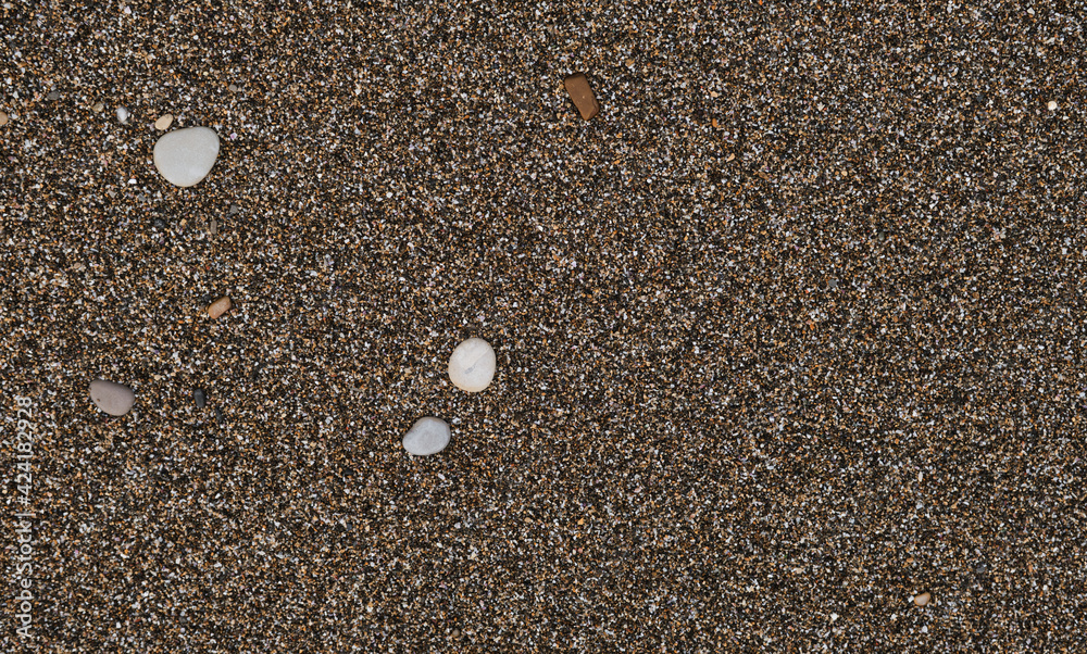 The Black Sea coast and its shore. Minimalistic sand background and space for text or ad design. Sand and small round stones close up. The Black Sea coast and its shore. Minimalistic sand background and space for text or ad design. Sand and small round stones close up.