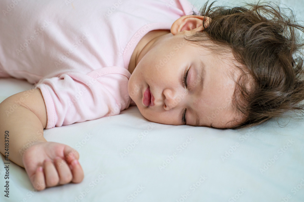 Little baby girl 12 months wearing pink cloth sleeping on white bed at home. Adorable one year old toddler mixed race asleep having good dream resting in the bedroom. Little baby girl 12 months wearing pink cloth sleeping on white bed at home. Adorable one year old toddler mixed race asleep having good dream resting in the bedroom.