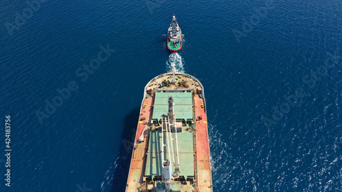 Aerial drone photo of huge crude oil tanker ship guided by tug boats