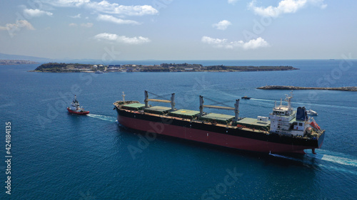 Aerial drone photo of cargo carrier tanker leaving industrial port of Perama with the help of tug boats for Mediterranean destination, Attica, Greece
