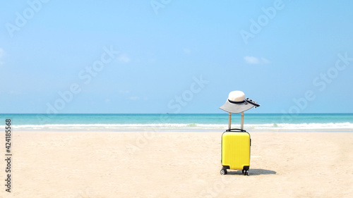 Travel on Summer and tourist planning with yellow suitcase with white hat fashion in the beautiful beach. Travel in holiday. Blue sky and sand background, on travel in summer concept. © EEarth