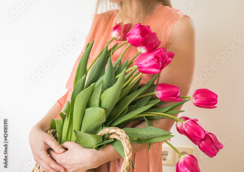 Beautiful young girl in dress holding big bouquet of tulips isolated over white background