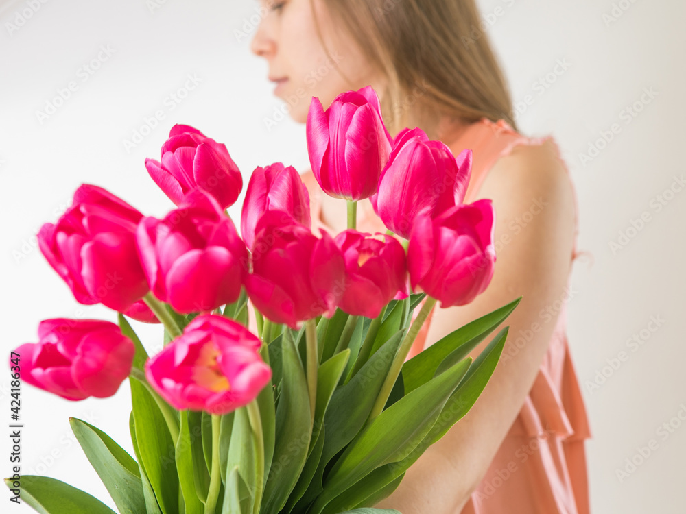 Beautiful young woman with tulip bouquet. Spring portrait. Bright pink flowers in girl's hands.