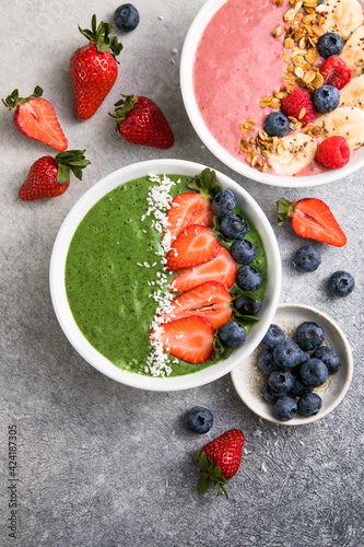 Matcha green tea breakfast superfoods smoothies bowl topped with strawberries, blueberries, coconut flakes Overhead, top view, flat lay