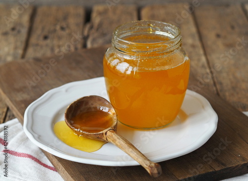 Wooden spoon with a jar of natural rustic honey from a private apiary on a plate.The concept of the health benefits of honey.