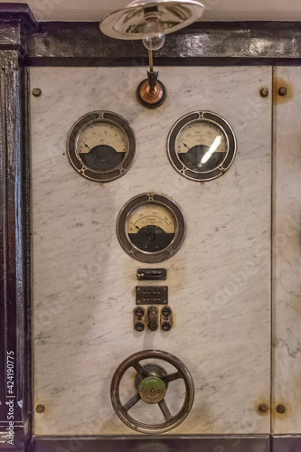 Detailed view of a old control panel with thermostat and pulley, from a classic 1934 industrial hydroelectric generator engine