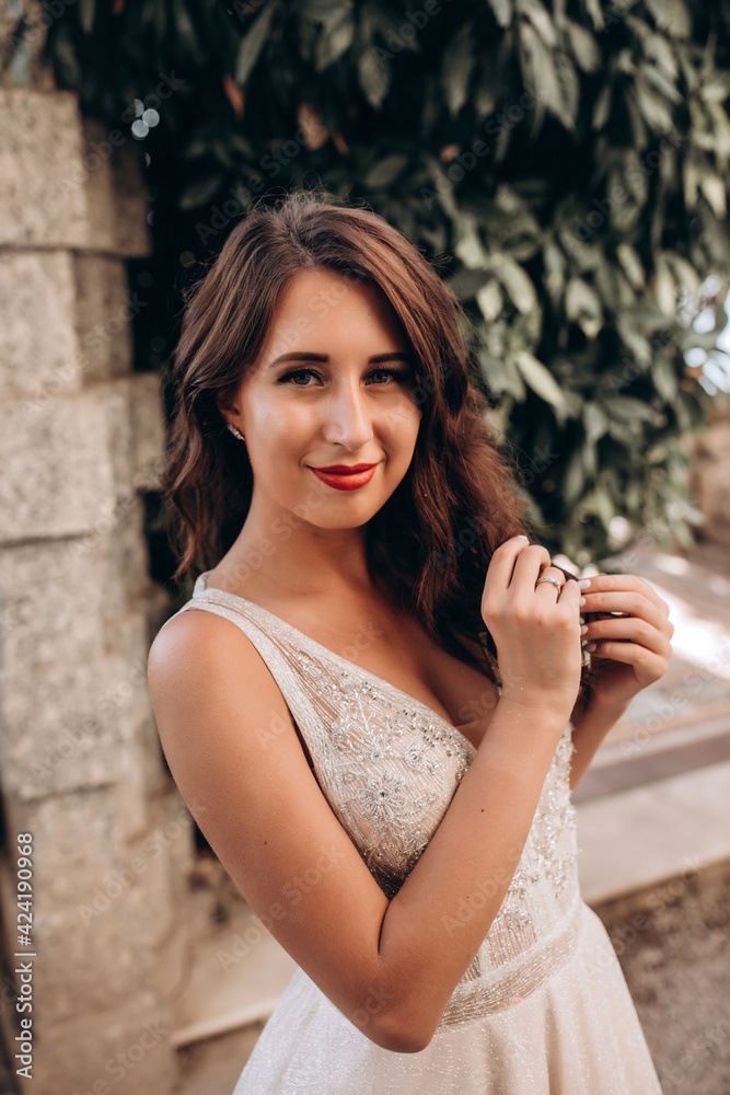 Obraz premium Portrait of the bride. The girl's walk through the old estate. Bride in a wedding dress for the upcoming ceremony. The path to the groom. Summer sunny day.