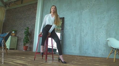 A young blonde girl in a white blouse sitting on the chair