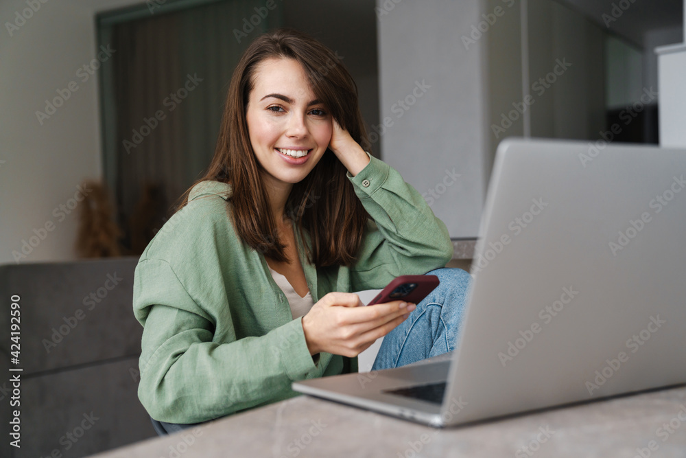 Young smiling woman using laptop while working with laptop at home