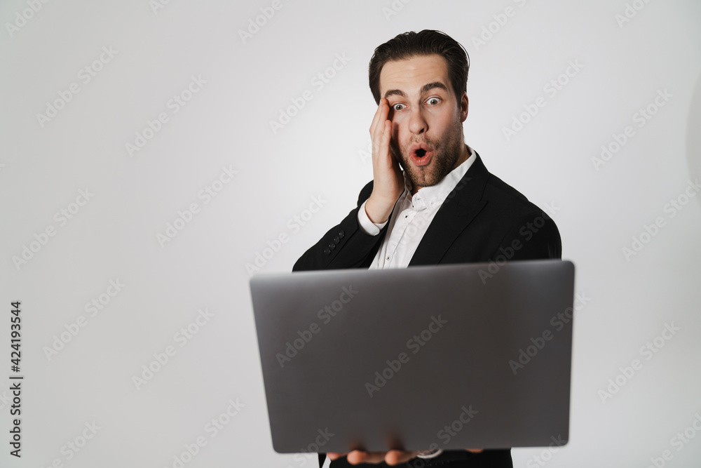 Unshaven shocked man in jacket expressing surprise while using laptop Unshaven shocked man in jacket expressing surprise while using laptop