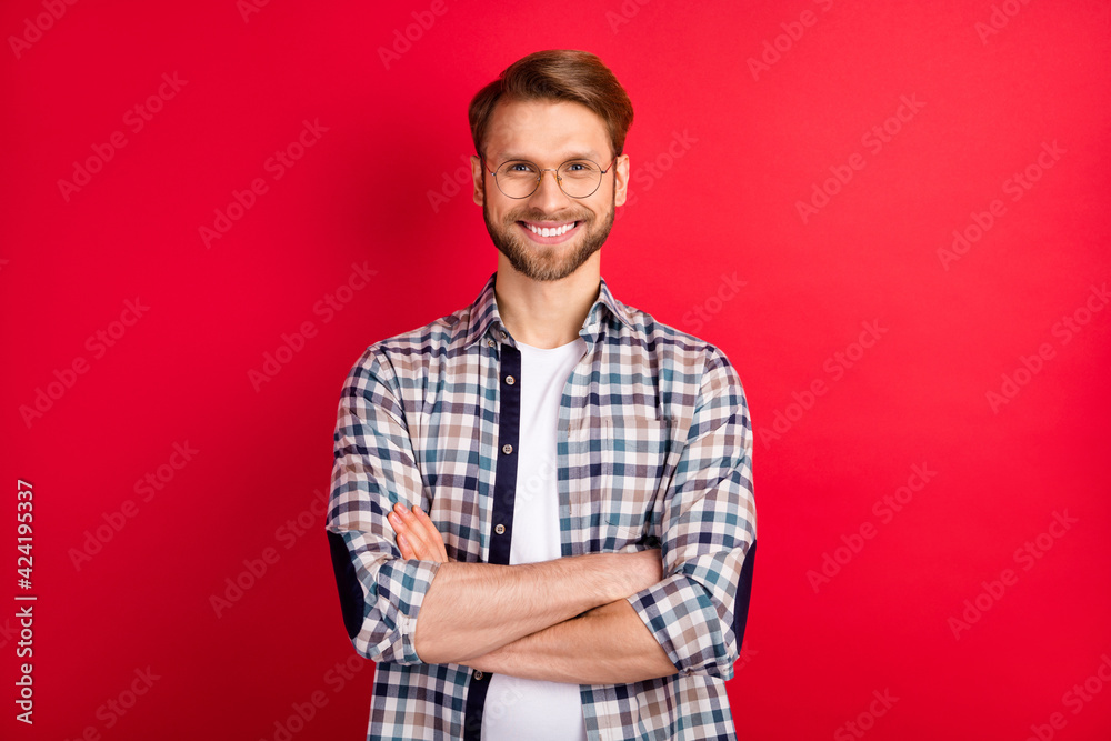 Fototapeta premium Photo of pretty confident young gentleman dressed plaid shirt spectacles hands folded smiling isolated red color background