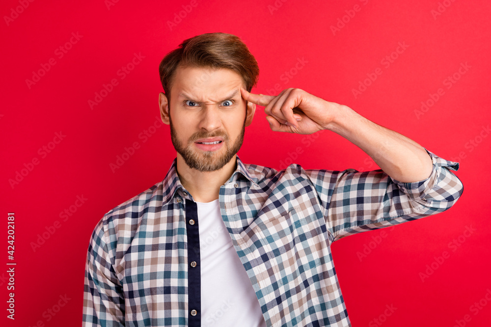 Photo of young handsome man unhappy sad upset negative finger touch head stupid sign accuse isolated over red color background Photo of young handsome man unhappy sad upset negative finger touch head stupid sign accuse isolated over red color background