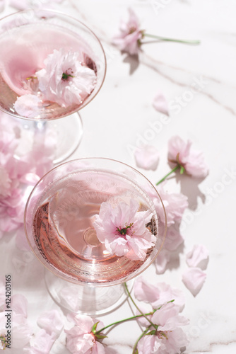 Rose light champagne in the two rare coupes champagne glasses with beautiful soft flowers. Summer drink for party, wine shop or wine tasting concept