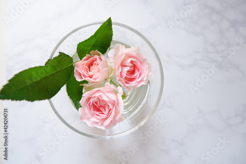 Spring greeting concept. Pink roses in a transparent vase on the white marble background. Wedding, Bridal, Mother's day and Birthday. ピンク薔薇とカード、結婚式、母の日、誕生日のデコレーション背景