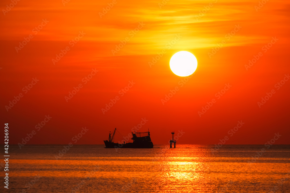 A silhouette fishing boat on the bay in the morning and sunrise on the sky