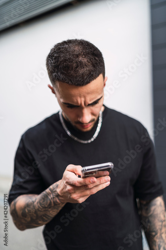 Chico manejando smartphone vestido con ropa negra © MiguelAngelJunquera