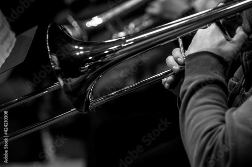 Hands of a musician playing the trombone close-up in black and white