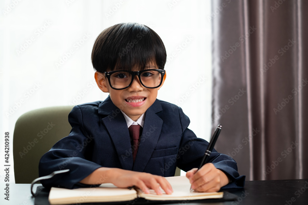 Little boy in business suit write someting on the book Little boy in business suit write someting on the book