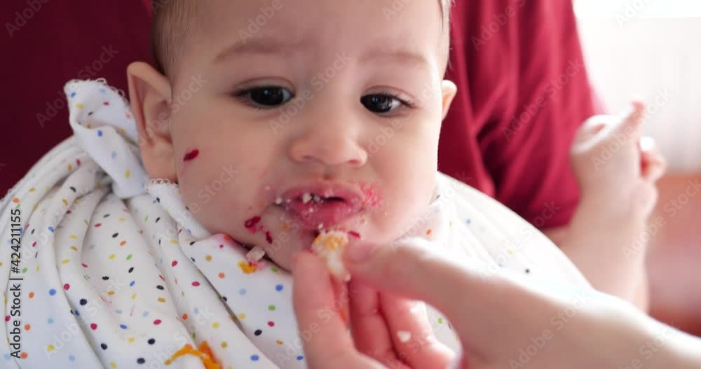 mother holds the baby in her arms and feeds her boy with a spoon. family, food, child, eating and parenthood concept mother holds the baby in her arms and feeds her boy with a spoon. family, food, child, eating and parenthood concept
