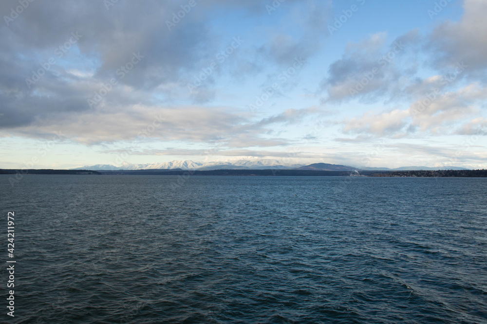 Fototapeta premium The Olympic mountains of Washington State viewed from across the water covered in snow.
