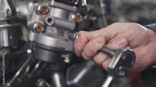 Close up of disassembled car engine. Hands of professional mechanic repairing motor. Repairer working in garage or workshop. Man engaged servicing cars