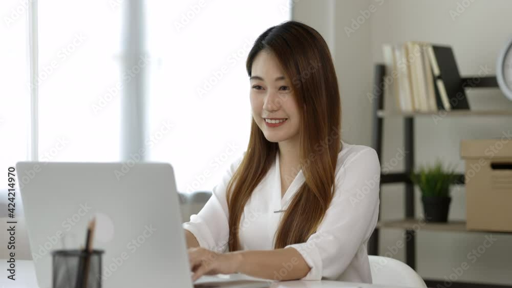 Young asian beautiful business woman working with laptop sitting at home. Smiling charming happy young female doing homework meeting conference with team at home. Young asian beautiful business woman working with laptop sitting at home. Smiling charming happy young female doing homework meeting conference with team at home.