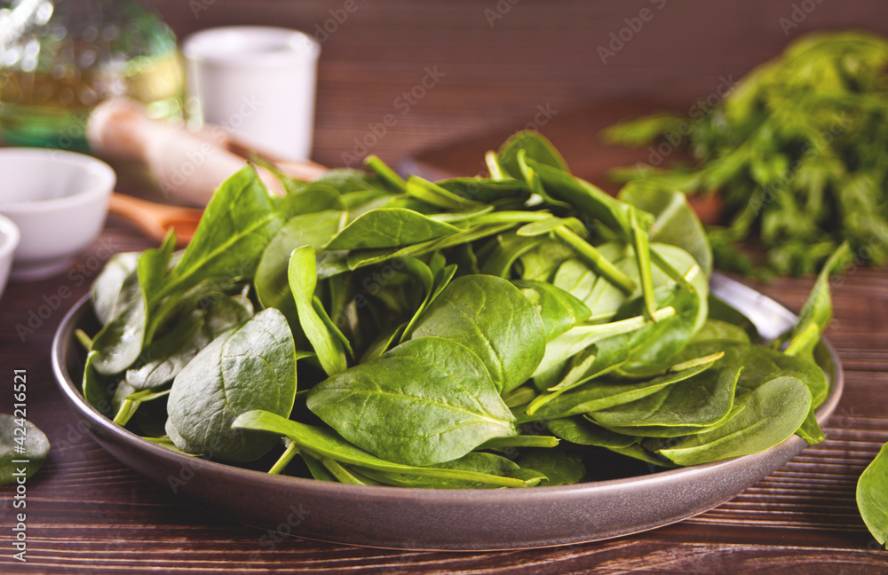 spinach on the plate on the dark wooden background spinach on the plate on the dark wooden background