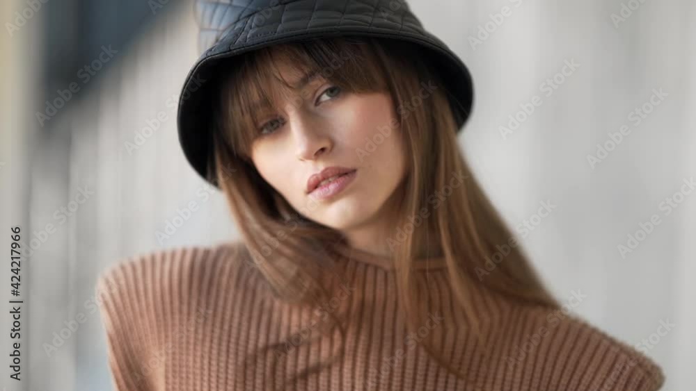 close-up portrait of a beautiful girl in a black panama hat hugging a leather bag
