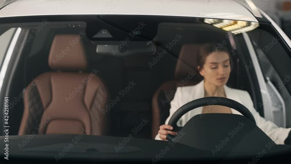 Stylish business woman sitting behind the wheel evaluates the new interior Stylish business woman sitting behind the wheel evaluates the new interior