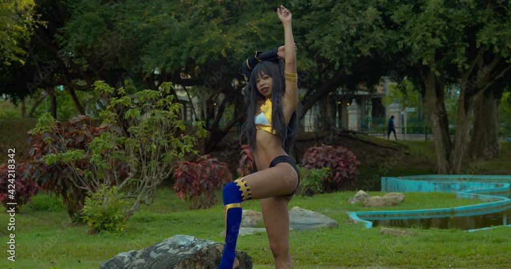 Sexy Ishtar Goddes cosplay costume girl standing in a garden with a manmade pool in the background