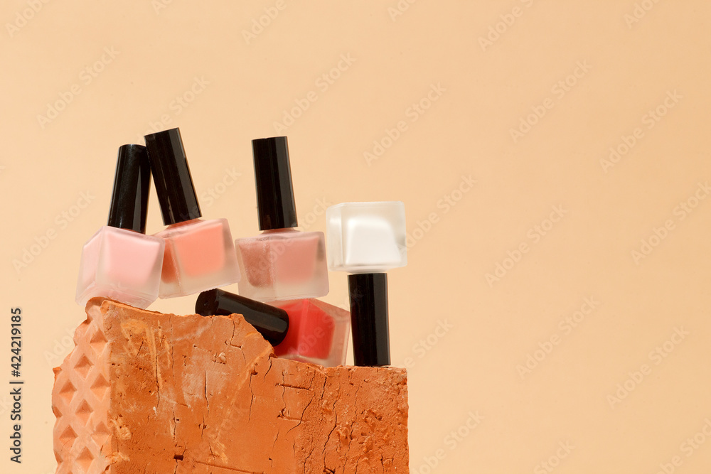 Set of nail polish bottles neutral natural colors on brick podium on beige background. Concept of pallete for french manicure, trendy modern stone platform for presentation of products