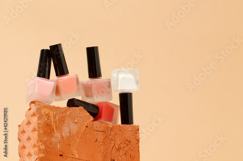 Obraz na płótnie Set of nail polish bottles neutral natural colors on brick podium on beige background. Concept of pallete for french manicure, trendy modern stone platform for presentation of products w salonie