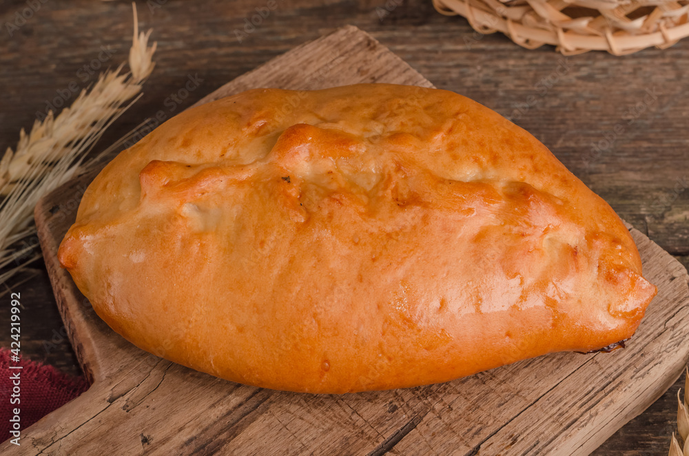 Appetizing fresh culinary pastry - filled patty on wooden