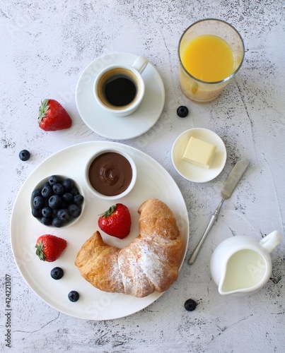 Breakfast: fresh pastries, espresso, butter, nutell, paste and berries on a white background, top view