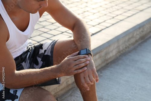 Man checking fitness tracker after training outdoors, closeup