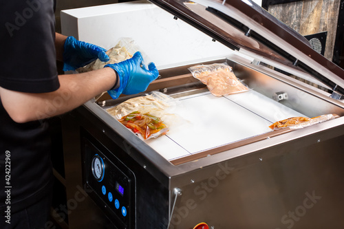 A view of a person preparing plastic sealed food bags in vacuum chamber sealer appliance. photo