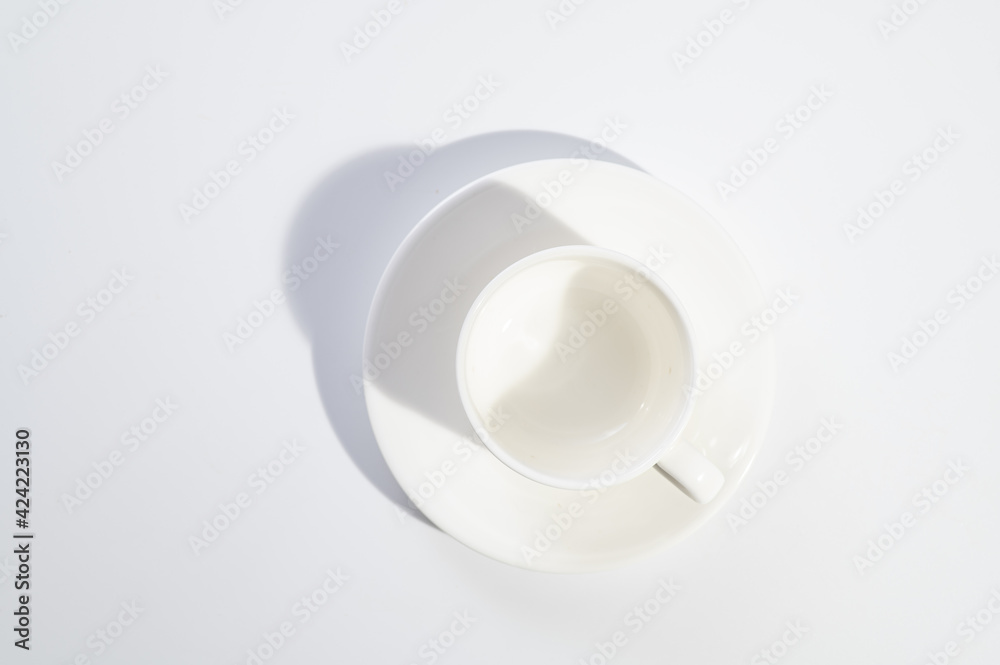 empty white cup and saucer on white background, hard light, shadow, top view empty white cup and saucer on white background, hard light, shadow, top view