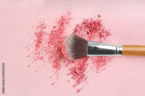 Foto Makeup brush and scattered blush on pink background, top view