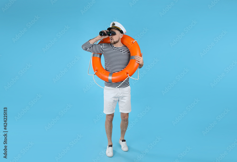Sailor with orange ring buoy looking through binoculars on light blue background Sailor with orange ring buoy looking through binoculars on light blue background