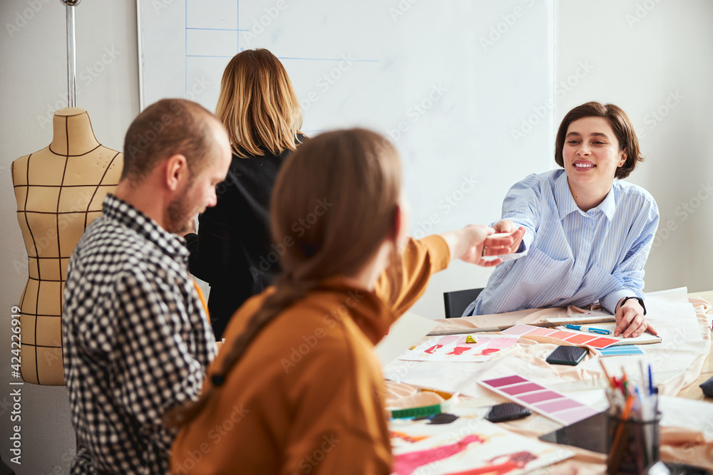 Obraz premium Positive designer sharing notes with her colleagues