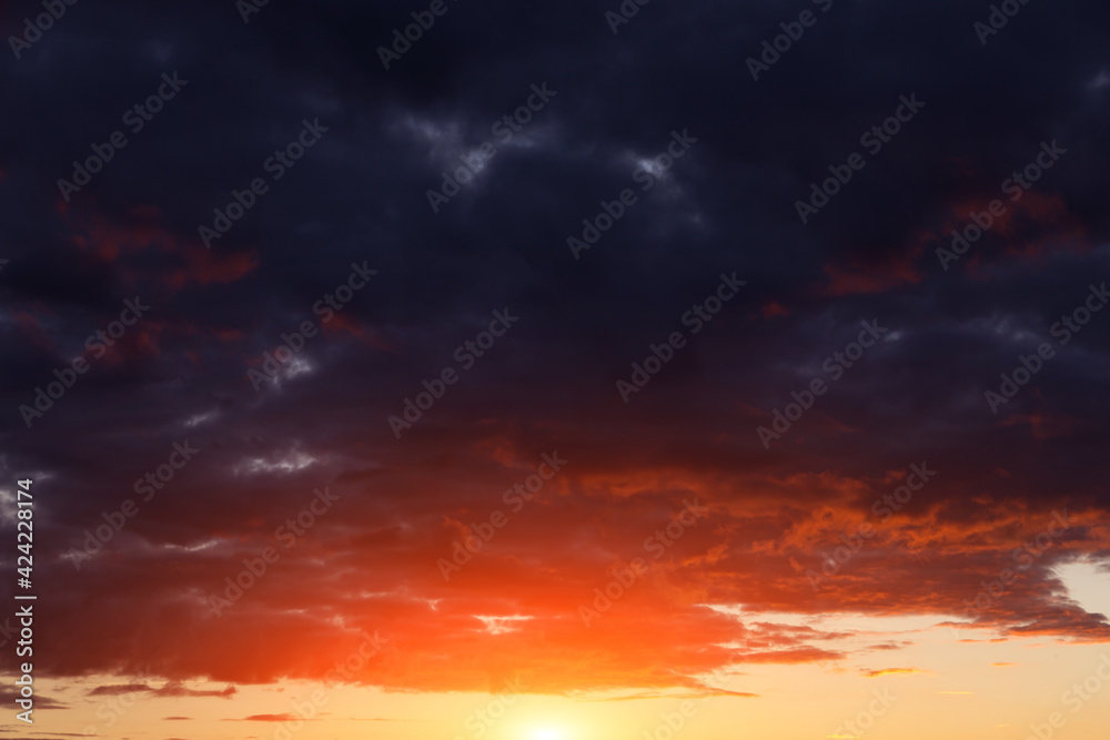 Epic dramatic sunset, sunrise on storm sky with dark clouds, orange yellow red sun and sunlight background texture	
