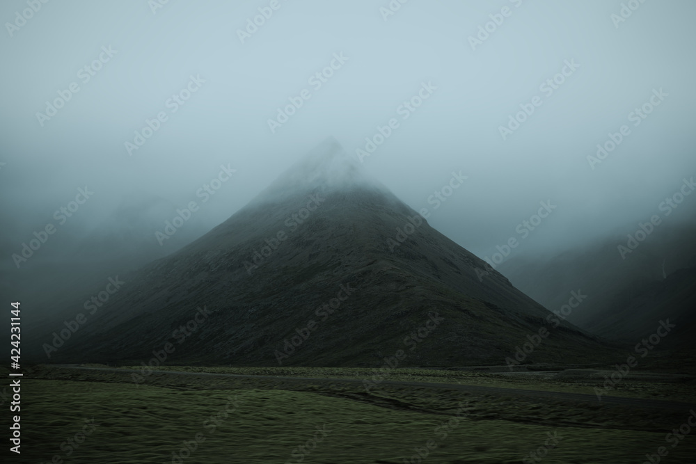 Beautiful nature dramatic landscape in Iceland. Low clouds, fog on the mountains. Cold toned filter