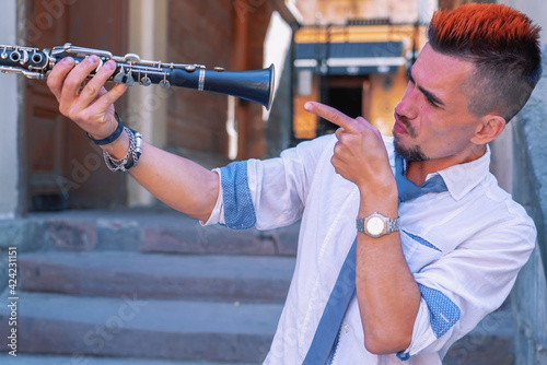 Funny image of male musician with clarinet outdoors in old European city. Horizontal image.