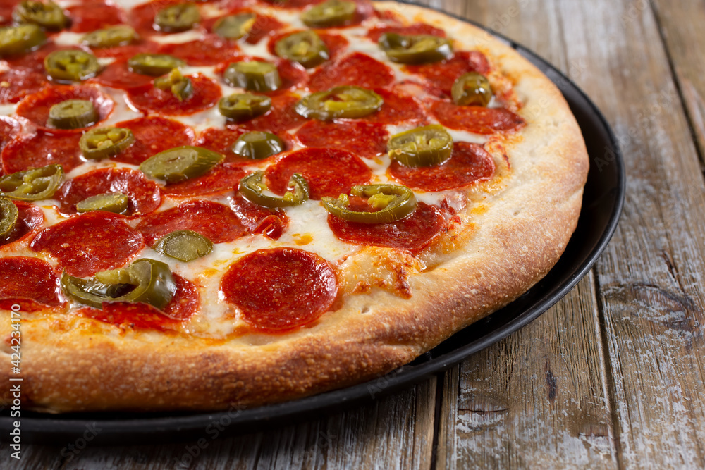 A view of a pizza pie featuring toppings as pepperoni and jalapeño.