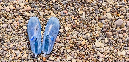 Rubber blue women's slippers for swimming on a pebble beach photo