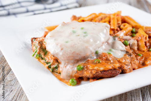 A view of chicken parmigiana and penne pasta.