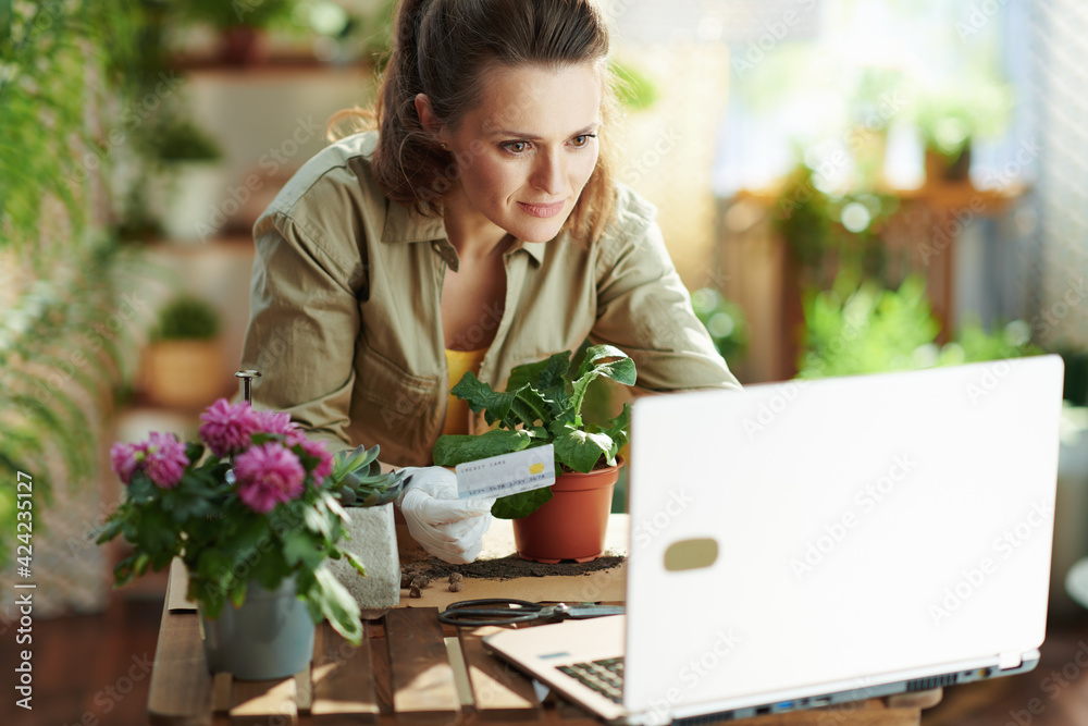 female in rubber gloves at home in sunny day buying on internet
