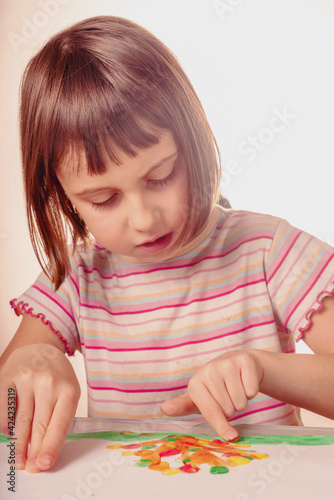 Beautiful young girl painting artwork with colorful hands and finger. Vertical image.