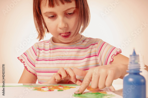 Beautiful young girl painting artwork with colorful hands and finger.
